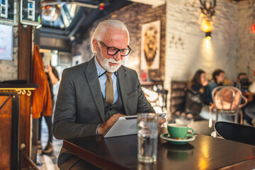 Senior man businessman business owner use digital tablet sit at cafe