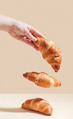 Fresh delicious croissants are held by a female hand, levitation.