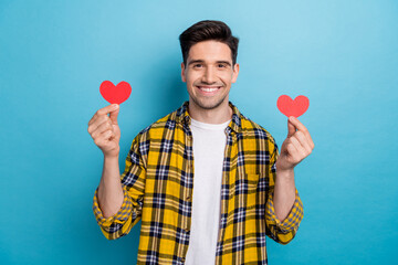 Photo of handsome boyfriend in casual trendy garment hold two red handmade postcards heart figure isolated on blue color background