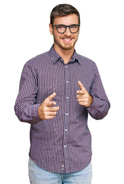 Handsome caucasian man wearing casual clothes and glasses pointing fingers to camera with happy and funny face. good energy and vibes.