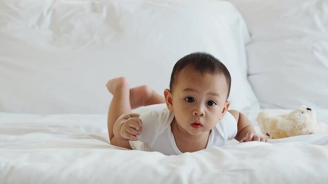 lovely asian baby on dress with innocent actions on bed