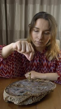 A young woman holding a moving pendulum over a large agate.