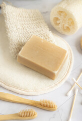 Beige handmade soap bar on soap saver bag near hygiene Items close up