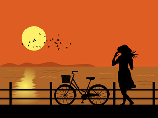 Silhouette of woman and bicycle standing by the sea watching the sunset.