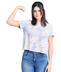 Obraz premium Young beautiful girl wearing casual t shirt strong person showing arm muscle, confident and proud of power