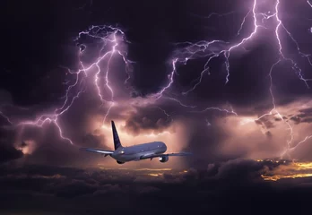 Schilderijen op glas passenger plane in a zone of turbulence, clouds and thunderstorms with lightning during flight, dangerous flight on an airplane. © velimir