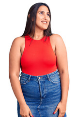 Young beautiful brunette woman wearing casual sleevelss t-shirt looking away to side with smile on face, natural expression. laughing confident.