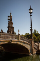 Fototapeta na wymiar Pituresque bridge and lamppost at the National Geographic Institute in Plaza de España Seville city Spain. Central government offices in stunning rich wealthy architecture design