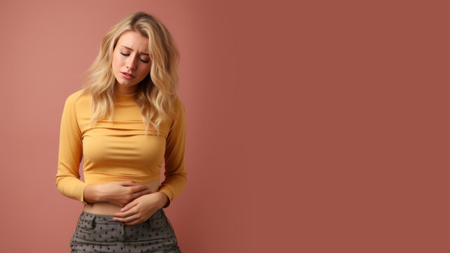 Blonde woman wincing in pain and hand rubbing stomach