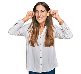 Young beautiful woman wearing casual clothes smiling pulling ears with fingers, funny gesture. audition problem