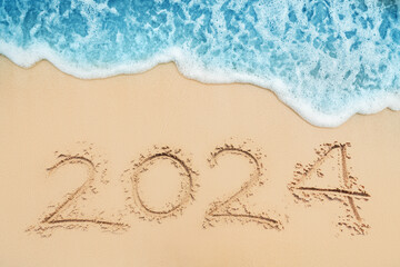 Fototapeta na wymiar Happy New Year 2024 text on tropical beach sand and turquoise water of caribbean sea