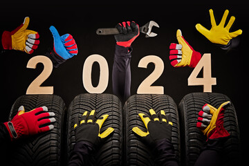 Winter car tires service and hands of mechanics, wrench and text 2024 happy new year on black...