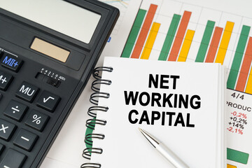 On business charts there is a calculator, a pen and a notepad with the inscription - NET WORKING CAPITAL
