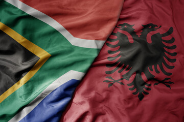 big waving national colorful flag of albania and national flag of south africa .