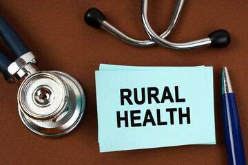 On a brown surface there is a stethoscope, a pen and blue stickers with the inscription - rural...