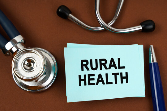 On a brown surface there is a stethoscope, a pen and blue stickers with the inscription - rural health