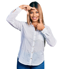 Young hispanic woman wearing casual white shirt smiling making frame with hands and fingers with happy face. creativity and photography concept.