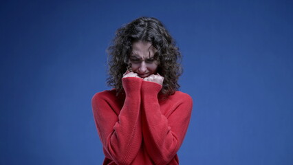 Upset young woman feeling angry clenching fists regreting moment standing on blue background....