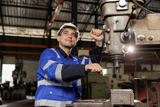 Male workers wearing uniform safety and hardhat working an iron cutting machine in factory. Engineering worker man work machine lathe metal.
