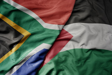 big waving national colorful flag of palestine and national flag of south africa .