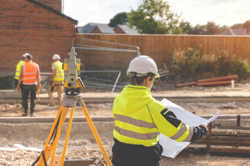 Construction site engineer woman in safety equipment working with surveying total station EDM...