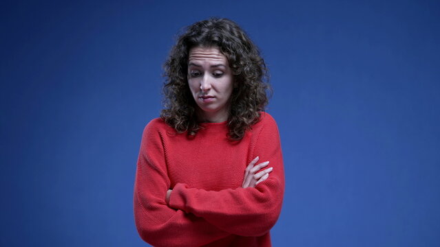 Woman feeling disgust and apprehension by crossing arms while feeling anxious and fearful standing on blue background, 20s female person in distraught stress emotion