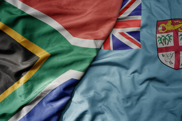 big waving national colorful flag of Fiji and national flag of south africa .