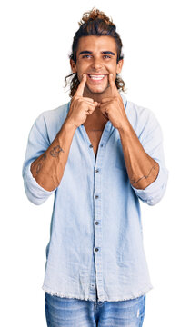Young hispanic man wearing summer style smiling with open mouth, fingers pointing and forcing cheerful smile