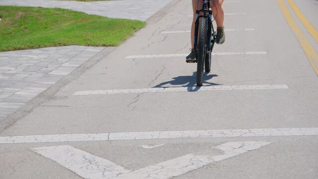 A woman rides a bicycle among green palm trees in tropical suburbs. Close up