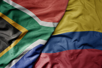 big waving national colorful flag of colombia and national flag of south africa .