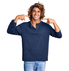 Young hispanic man wearing casual clothes smiling cheerful showing and pointing with fingers teeth and mouth. dental health concept.