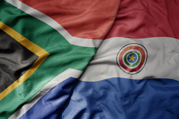 big waving national colorful flag of paraguay and national flag of south africa .