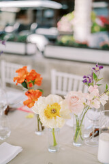 Obraz na płótnie Canvas Bright flowers stand in glass vases on a festive table 