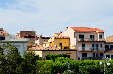 Fototapeta na wymiar Landscape view of red tile rooftops of colored residential houses against blue sky. Typical architecture of city in Sicily. Santo Stefano di Camastra, Italy. Travel and tourism concept