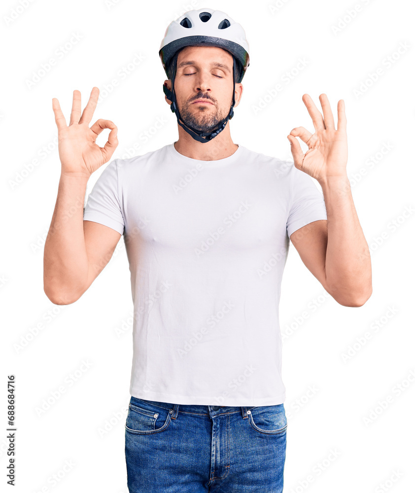 Wall mural Young handsome man wearing bike helmet relax and smiling with eyes closed doing meditation gesture with fingers. yoga concept.