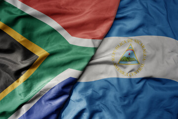big waving national colorful flag of nicaragua and national flag of south africa .