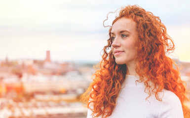 Closeup portrait of a young happy woman with red curly hair  toned image