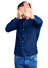 Young handsome man wearing casual shirt covering eyes with hands and doing stop gesture with sad and fear expression. embarrassed and negative concept.