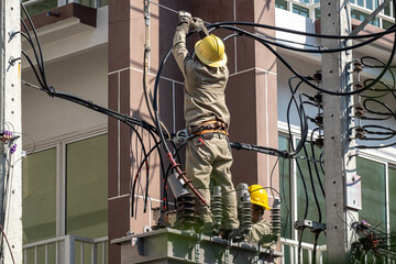 Two Electricians are Repairing an Electrical Transformer atop a High-Voltage Electrical Pole Outdoor