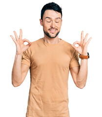 Hispanic man with beard wearing casual t shirt relaxed and smiling with eyes closed doing meditation gesture with fingers. yoga concept.