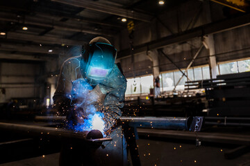 The welder works in the workshop. The moment of welding of metal structures. Beautiful sparks during welding of various metal elements in the workshop. The welder is working hard. - 688688348