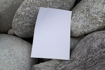 Mockup of white A4 sheet on large gray stones of mountain rivers. Layout of poster on stone...