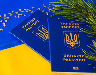 Ukrainian passport, Christmas tree branches and gold stars on the background of the Ukrainian flag.
