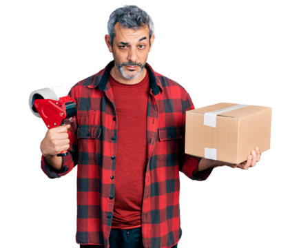 Middle age hispanic with grey hair holding packing tape and cardboard box skeptic and nervous, frowning upset because of problem. negative person.