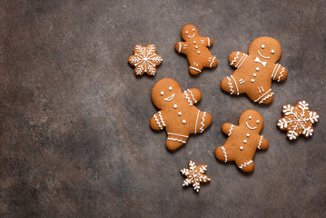 Gingerbread cookies men and snowflakes on a dark brown background. Top view, flat lay, copy space. Christmas composition.