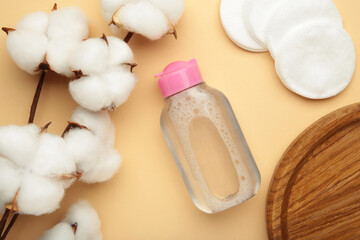 Micellar cleansing water and cotton pads on beige background. Vertical photo