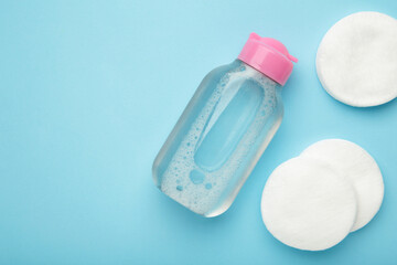 Micellar cleansing water and cotton pads on blue background. Space for text