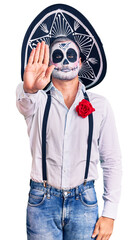 Man wearing day of the dead costume over background doing stop sing with palm of the hand. warning expression with negative and serious gesture on the face.