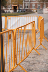 Fototapeta na wymiar Yellow construction workers fence around pavers working in old part of urban area.