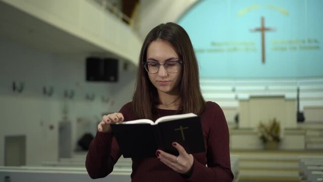 A young woman reads the Bible in church